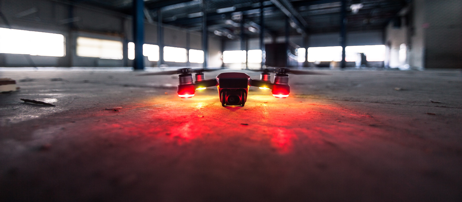 Dron con luces de posición en vuelo dentro de una nave industrial